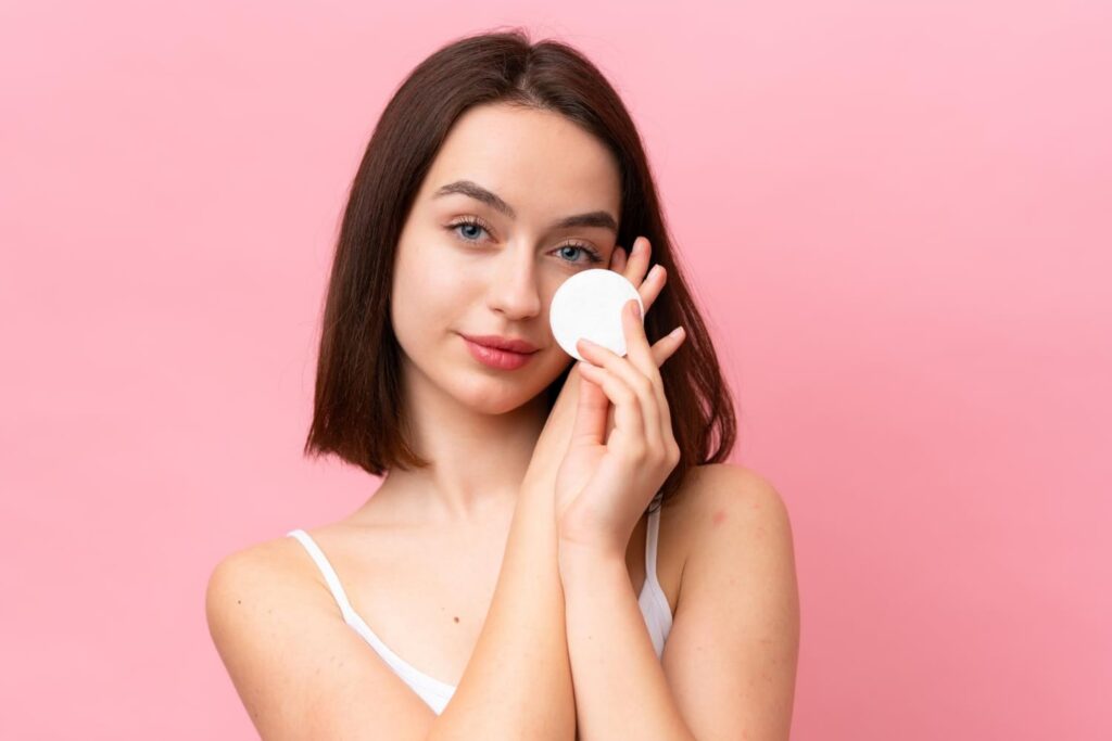 A woman cleanses her face using a cotton pad and the best micellar water